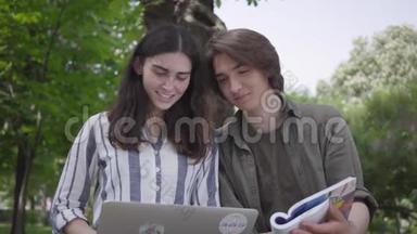 男生和女生穿着便服坐在长凳上，女生拿着笔记本电脑，男生手里拿着日记